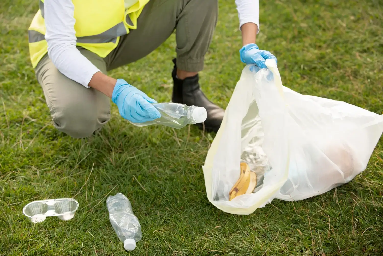 Person collecting trash with gloves and a bag